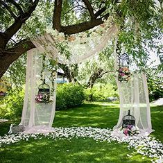 an outdoor ceremony setup with flowers and birdcages on the grass, surrounded by trees