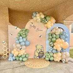 a winnie the pooh birthday party with balloons and honeycombs on display in front of an arch