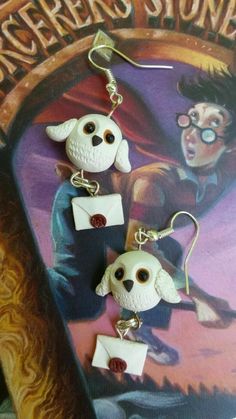 harry potter earrings with owl charms on them are shown in front of a book cover