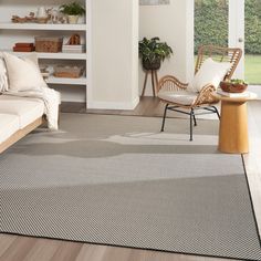 a living room with white walls and wooden floors is pictured in this image, there are two wicker chairs sitting on the floor