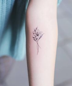 a woman's arm with a small flower tattoo on the left side of her arm