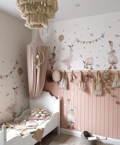 a bedroom with pink walls and white bedding, hanging decorations on the wall above it