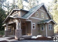 a house in the woods with lots of trees and rocks on the front lawn area