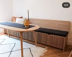 a room with a table, bench and rug on the floor in front of it