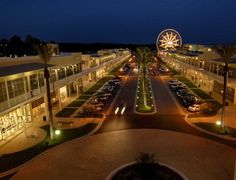 an aerial view of a street at night with cars parked on both sides and ferris wheel in the distance