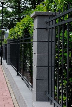 a black iron fence next to a brick sidewalk