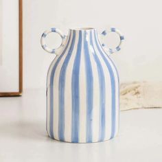 a blue and white striped vase sitting on top of a table next to a mirror