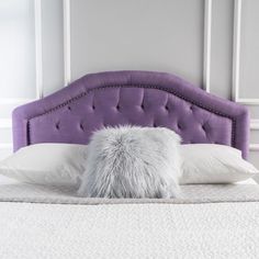 a bed with a purple headboard and white pillows