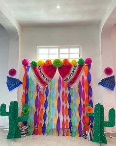 a room decorated in bright colors with cactus decorations on the wall and colorful curtains hanging from the ceiling