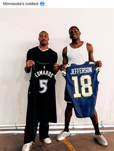 two young men holding jerseys in front of a white wall