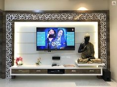 a buddha statue sitting in front of a flat screen tv mounted on a white wall