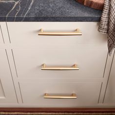 a kitchen counter top with gold handles and pulls on it's drawers, next to a rug