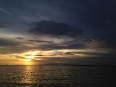 the sun is setting over the ocean with clouds in the sky and on the water