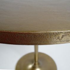 a close up view of a gold colored table with round base and metal ring at the top