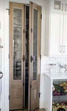 a kitchen with two glass doors and white cabinets