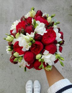 a bouquet of red and white flowers in someone's hand