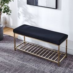 a gray bench sitting on top of a rug next to a potted plant in a living room