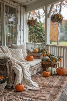 the porch is decorated with pumpkins and wicker furniture