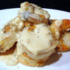 some kind of food that is on a white plate with gravy and shrimp