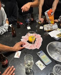 a group of people sitting around a table with cards and drinks in front of them