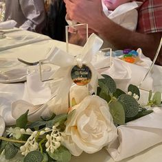 a baby is being held in the middle of a table with white flowers and greenery