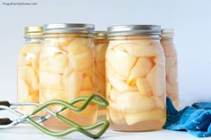 three mason jars filled with pickles next to a pair of tongs