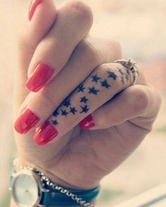 a woman's hand with red fingernails and stars on her fingers, holding onto the wrist