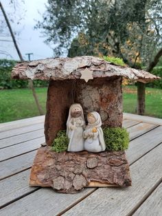 a nativity scene on a wooden table in the middle of a park with trees and grass