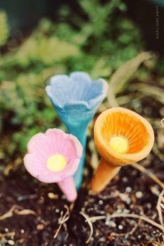 two small plastic flowers sitting in the dirt