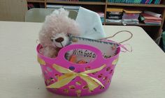 a teddy bear in a pink basket on a table