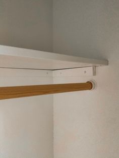 a white shelf with a wooden handle hanging from it's side