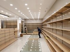 two men are standing in the middle of a large empty room with lots of shelves