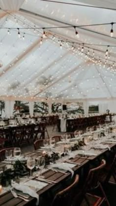 an indoor tent with tables and chairs set up for a wedding reception under string lights