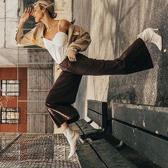 a woman leaning against a wall with her leg in the air