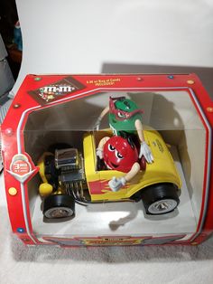 a yellow toy car with a green helmet on top in a red and white box