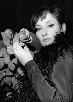 a woman holding a rose in her right hand and looking at the camera, black and white