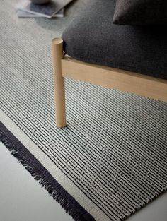 a black and white rug with a wooden frame on the floor next to a chair