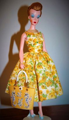 a doll is holding a purse and wearing a yellow dress