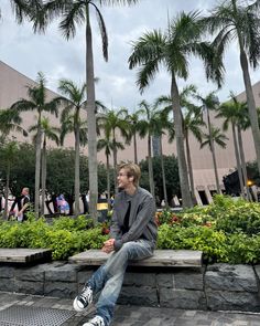 a man sitting on a bench in front of palm trees