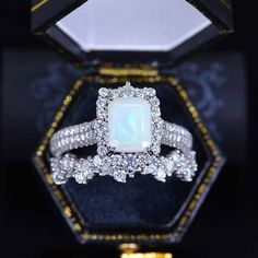 an opalite and diamond ring in a black box with gold trimmings