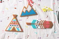 three pieces of bead art on a table with scissors and sprinkles