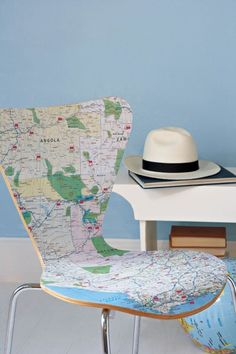 a white hat sitting on top of a chair next to a desk with a map