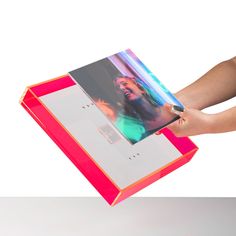 a person holding an open photo album in their left hand, with the cover opened to show a woman's face