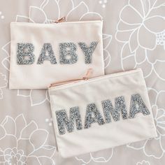 two baby mama bags sitting on top of a flower covered bed with the words baby mamma written in silver sequins