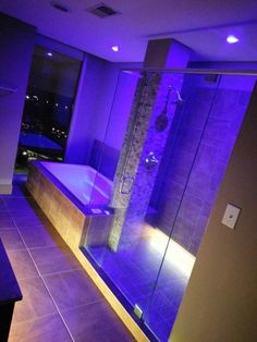 a bath room with a walk in shower and a purple light on the wall next to it