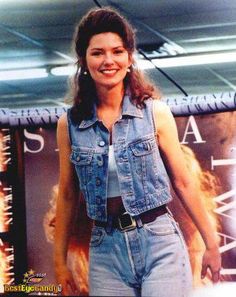 a woman is walking down the runway in denim overalls and a jean vest with an embellishment on her chest