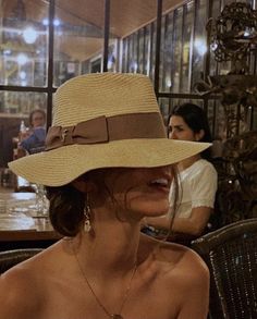 a woman sitting at a table wearing a hat