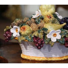 a white vase filled with lots of different types of flowers and fruit on top of a wooden table