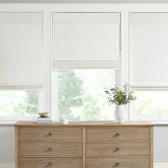 an empty room with white blinds on the windowsill and a wooden dresser in front of it