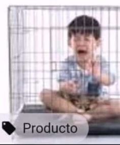 a young boy sitting in front of a cage holding a cat